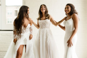 3 beautiful and laughing brides to be modeling different styles of wedding dresses purchased at Ivoryology