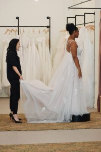 bridal store employee lifts train of bridal dress