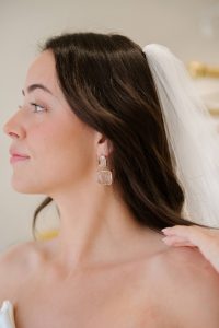 Bride to Be trying on chunky bridal earrings with her wedding veil.