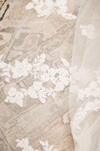 Close up of a bridal veil from Ivoryology with lace, floral appliques on the hem.
