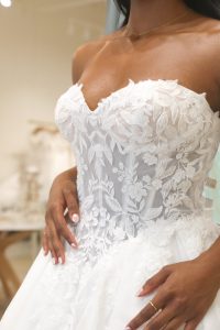 Detail shot of an affordable off-the-rack strapless wedding gown featuring textured floral lace overlays found at Ivoryology